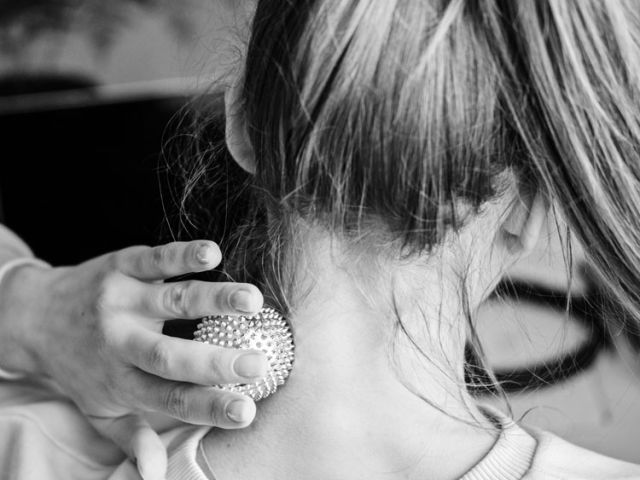 Mujer aplicando una pelota de masaje en la zona cervical para aliviar la tensión del cuello.