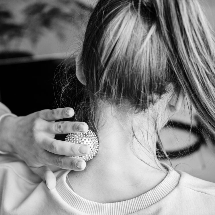 Mujer aplicando una pelota de masaje en la zona cervical para aliviar la tensión del cuello.
