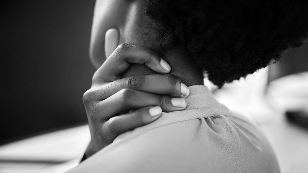 Persona sujetándose el cuello y el hombro, representando dolor cervical y tensión muscular asociada al teletrabajo.